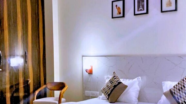 A hotel room with a large bed, a ceiling fan, and a modern design. - Cassava Stay (New Delhi)