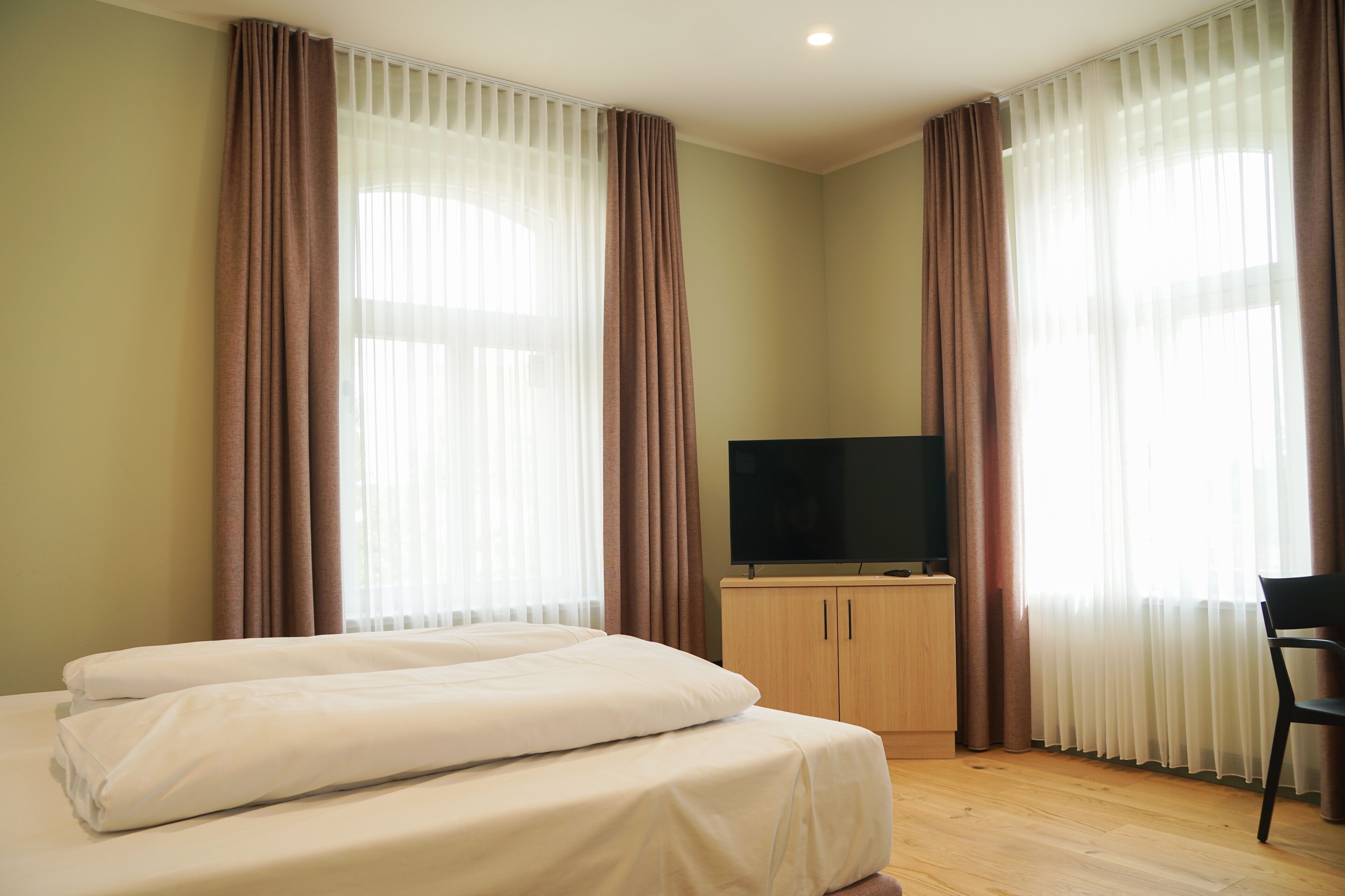 Ein Hotelzimmer mit Bett, Fernseher und Schreibtisch.