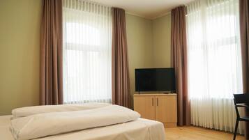Ein Hotelzimmer mit Bett, Fernseher und Schreibtisch.