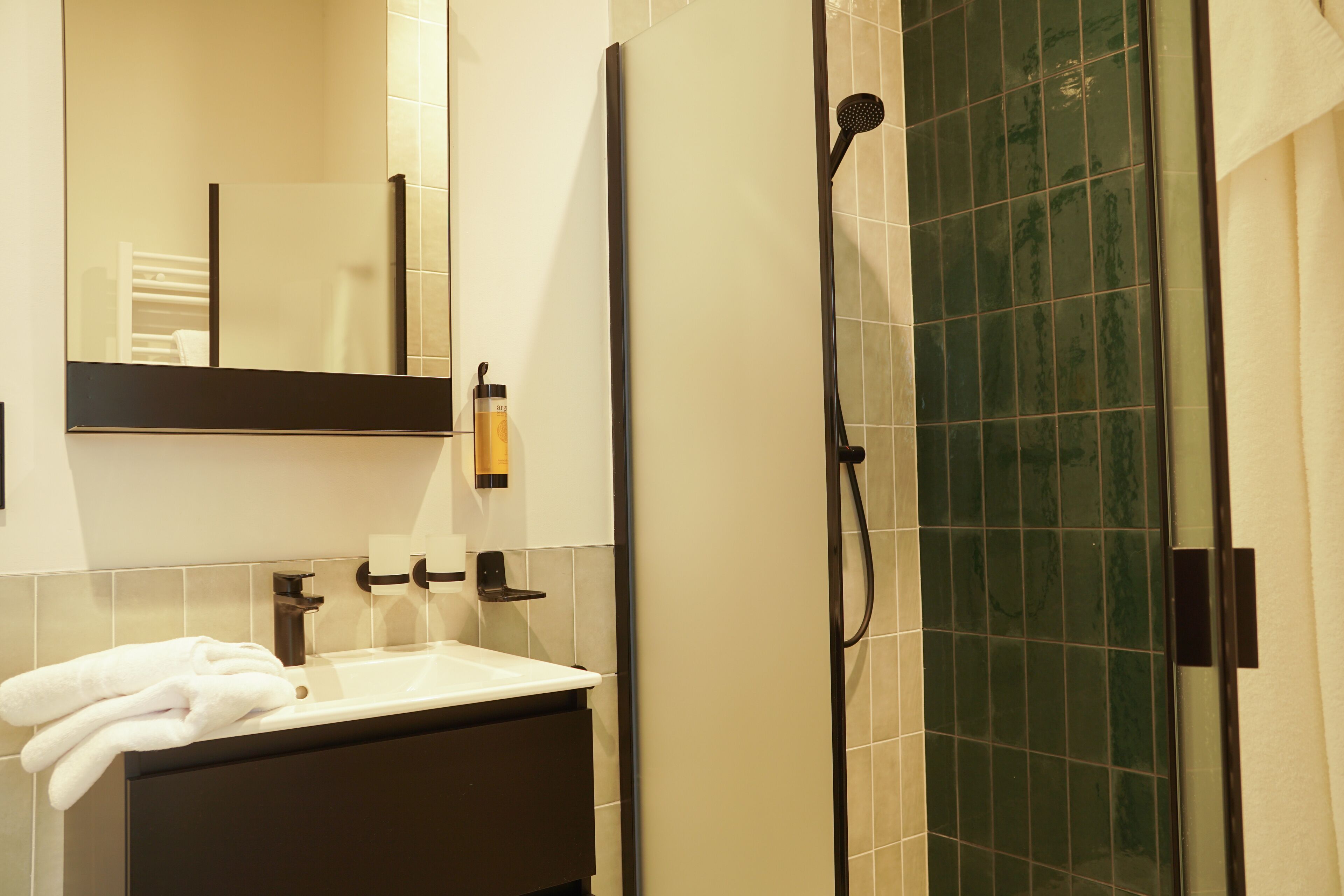 Un baño con lavamanos, espejo y ducha.