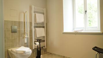 Ein Badezimmer mit Toilette, Handtuchhalter und Fenster.