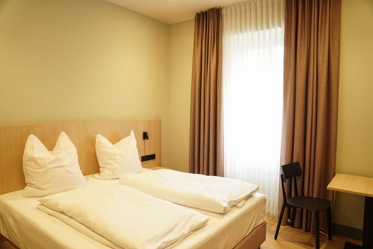 A hotel room with two beds, a desk, and a chair.