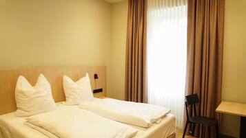A hotel room with two beds, a desk, and a chair.