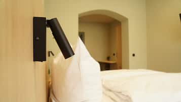A hotel room with a bed, a pillow, a wall-mounted light fixture, and an arched doorway.