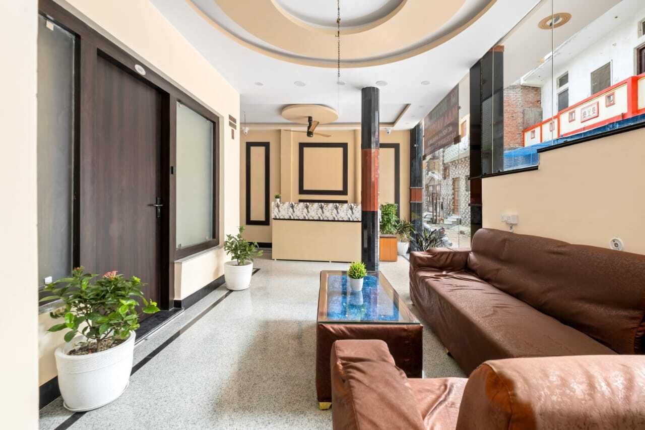 A modern lobby with a brown sofa, a glass coffee table, and potted plants.