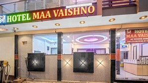 The exterior of Hotel Maa Vaishno with a modern facade, large glass windows, and a prominent neon sign. - Hotel Maa Vaishno (Ayodhya)