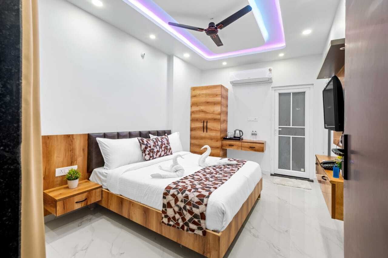 A modern bedroom with a wooden headboard, a bed with white linens, a decorative swan on the bed, a wooden wardrobe, and a ceiling fan.