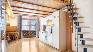 Una cocina moderna con armarios de madera, un área de comedor con una mesa y sillas, y una escalera de caracol.