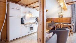 Una cocina moderna con armarios blancos, una zona de comedor con mobiliario de madera y un techo estilo loft.