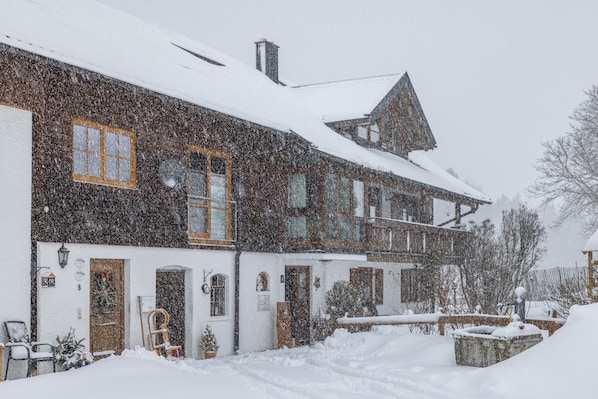 A two-story building with a snow-covered roof and a visible front door.