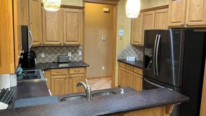 A kitchen with wooden cabinets, a black refrigerator, and a granite countertop. - Del City 6 Bed 2.5 Bath-Sleeps 14!, The Gathering-Spacious 6 Bedroom (Del City)