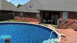A swimming pool with a wooden deck, a brick house, and a covered patio area. - Del City 6 Bed 2.5 Bath-Sleeps 14!, The Gathering-Spacious 6 Bedroom (Del City)