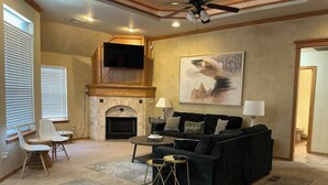 A living room with a fireplace, a black sofa, a round coffee table, and a painting on the wall. - Del City 6 Bed 2.5 Bath-Sleeps 14!, The Gathering-Spacious 6 Bedroom (Del City)