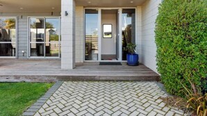 Een modern huis met een overdekte patio, een verzorgd gazon en een grote potplant.