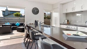 Een moderne keuken met een centraal eiland, barkrukken en een zithoek met een bank en stoelen.