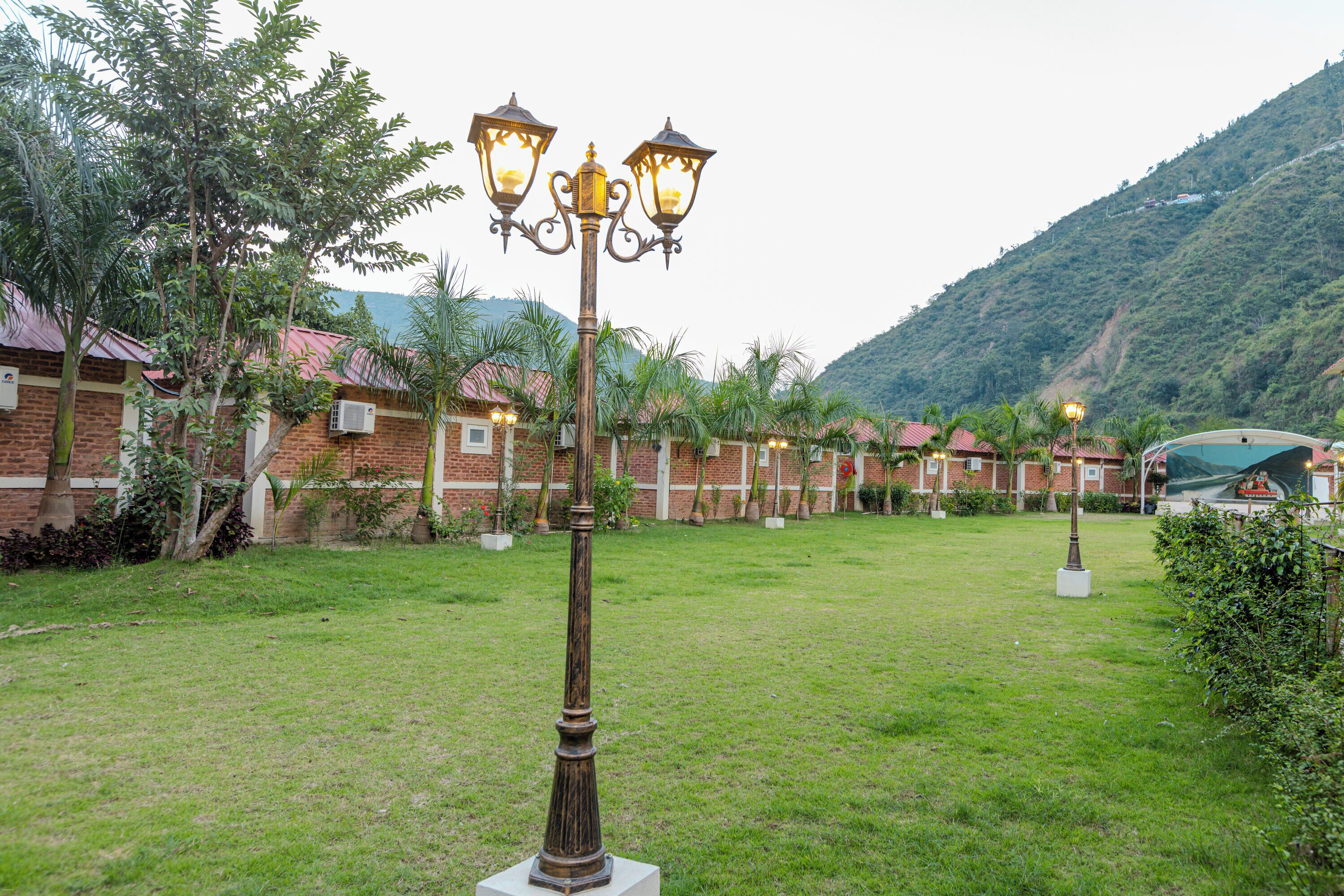 Une cour avec un lampadaire, des bâtiments en briques et une montagne en arrière-plan.