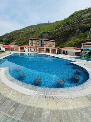 A swimming pool with a circular design, surrounded by stone tiles. - Kwality Beach Resort (Purano Jhangajholi)