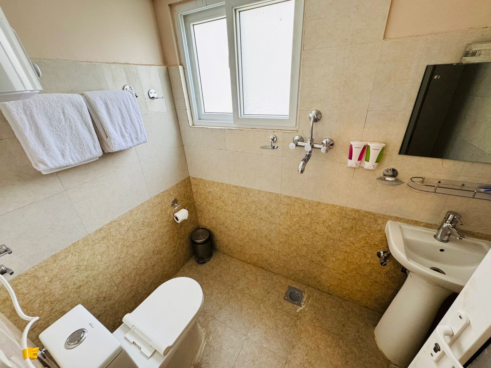 A bathroom with a toilet, bidet, sink, and a window.