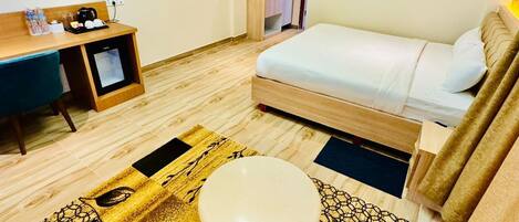 Habitación de hotel con cama, escritorio, televisor y un pequeño rincón de descanso.