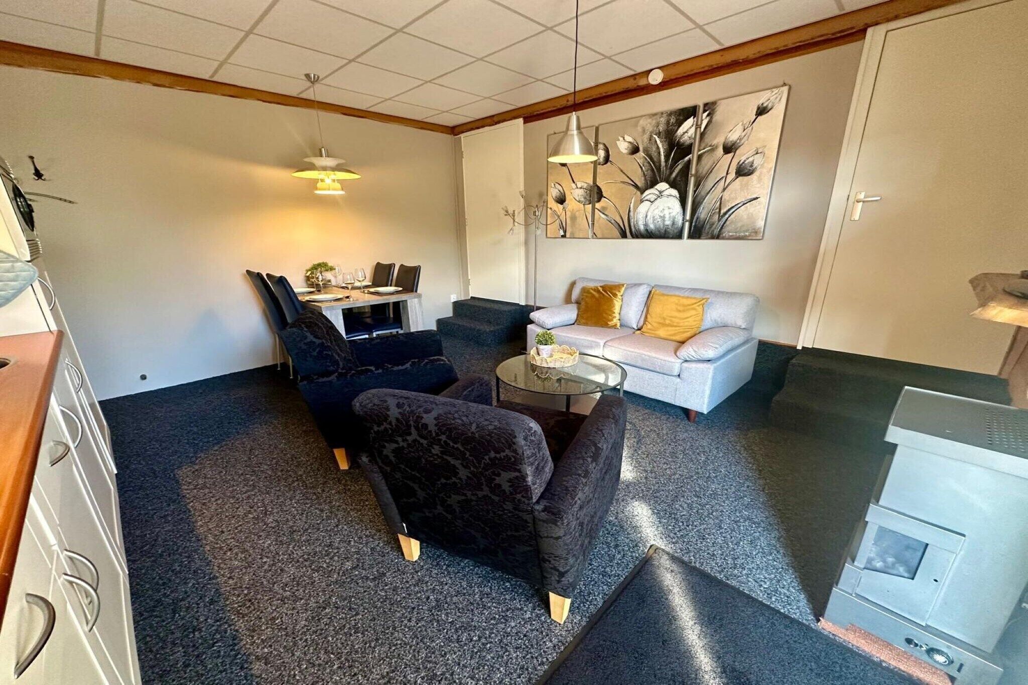 Un salon confortable avec un canapé, deux fauteuils, une table basse et un coin repas comprenant une table et des chaises.