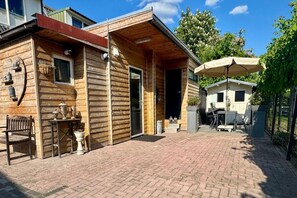 Une cabane en bois avec une terrasse en briques, une petite table et un banc.