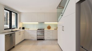 A modern kitchen with white cabinets, a stainless steel dishwasher, a gas stove, and a built-in oven.