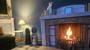 Un saló acollidor amb una llar de foc, un sofà, una làmpada i objectes decoratius.