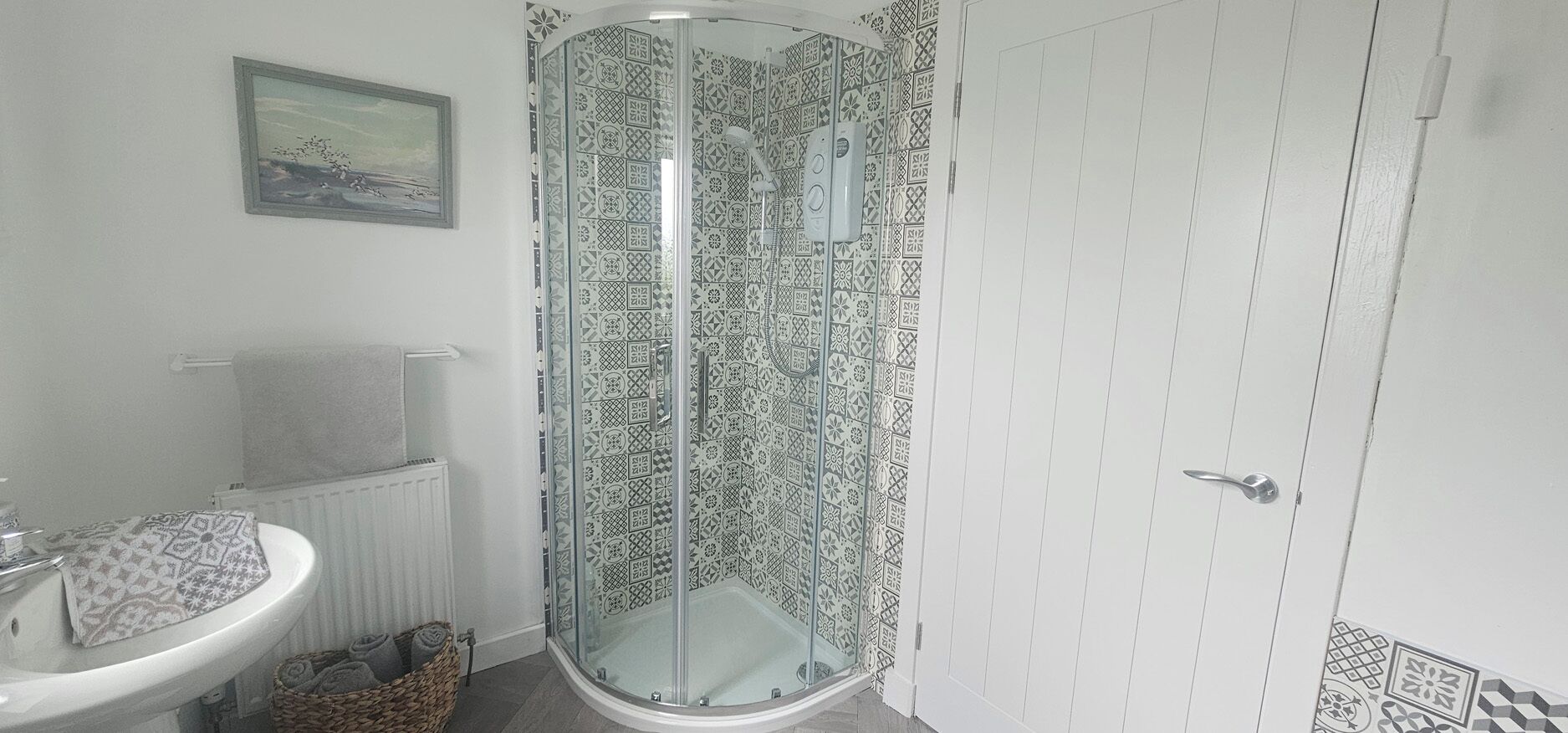 Une salle de bain avec une douche à parois de verre, un lavabo et un radiateur.