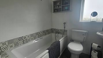 A bathroom with a bathtub, toilet, and sink.