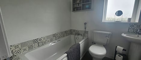 A bathroom with a bathtub, toilet, and sink.