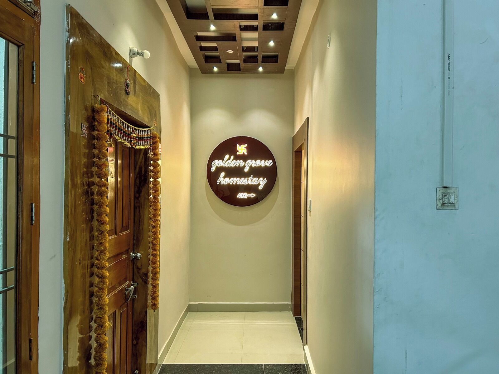 A hallway with a wooden door on the left, a wall-mounted sign reading "golden grove harnessary," and a ceiling with recessed lighting.