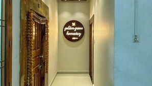 Un pasillo con una puerta de madera a la izquierda, un letrero en la pared que dice "golden grove harnessary" e iluminación empotrada en el techo.