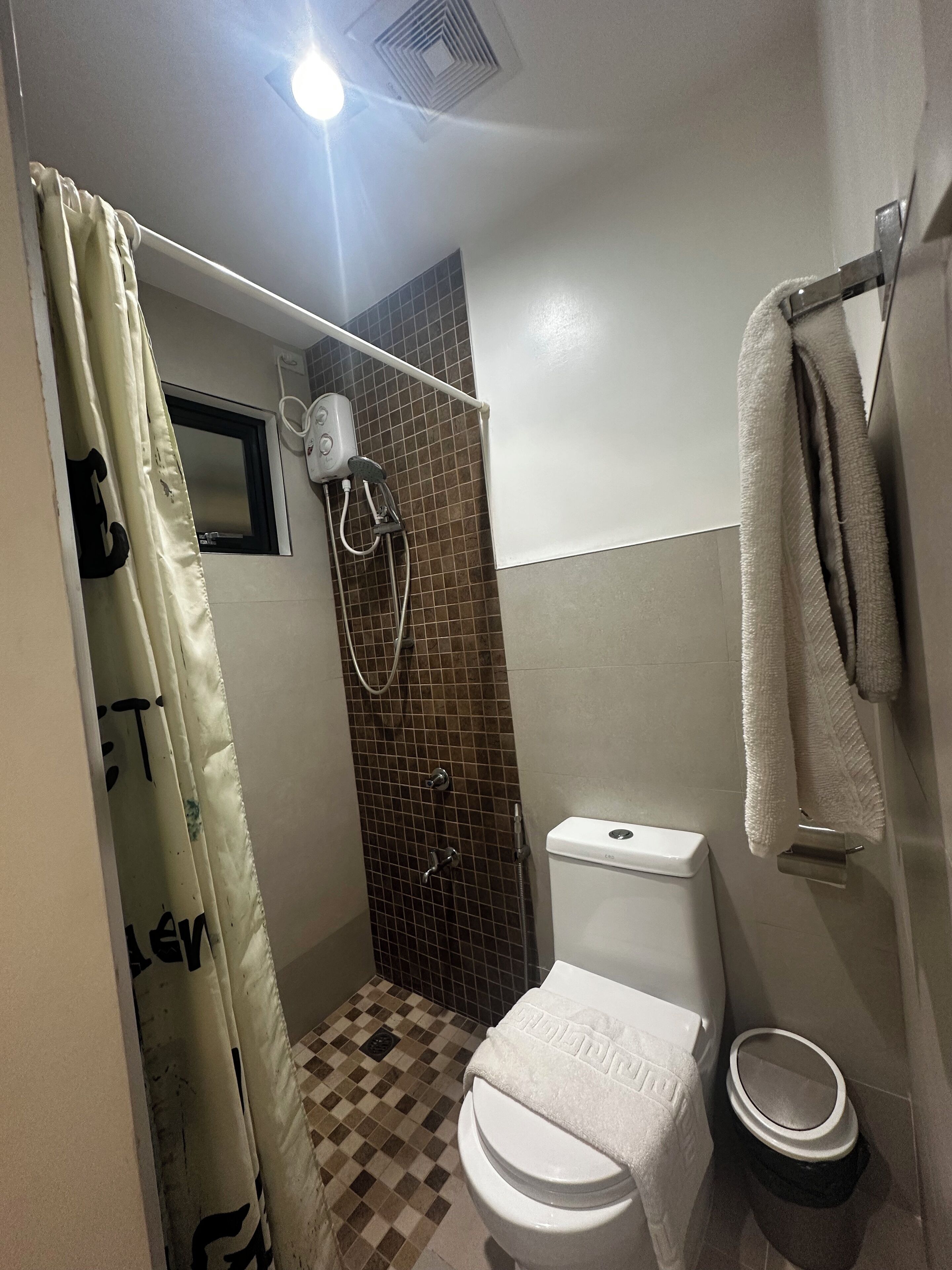 Un baño pequeño con ducha, inodoro y toallero.