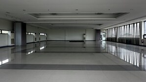 Un amplio y vacío vestíbulo de hotel con techo alto, ventanas grandes y suelo pulido.