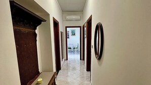 A hallway with a wooden bench, a mirror, and a door leading to a dining area. - Mistral's House - Apartment in the heart of Alghero (Alghero)