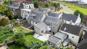 A residential area with houses, a grassy area, and a road leading to the sea. - Fife coastal corner (Buckhaven)