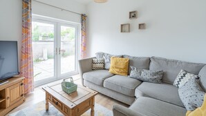 A living room with a grey sofa, a wooden coffee table, and a television on a wooden cabinet. - Fife coastal corner (Buckhaven)