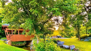 A wooden bridge over a stream, surrounded by lush greenery and a small building. - Free Dollywood Tix/HotTub/Dog Friendly/A+ Location (Sevierville)