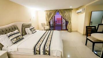 A hotel room with a large bed, a chair, a desk, and a view of the outside.