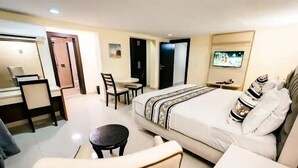 A hotel room with a bed, a desk, a chair, a TV, and a small table. - Harvey Trust Luxury Apartments (Kano)