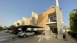 A multi-story residential building with a parking area in front. - Harvey Trust Luxury Apartments (Kano)