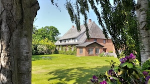 Une maison avec une grande pelouse et un toit de chaume.