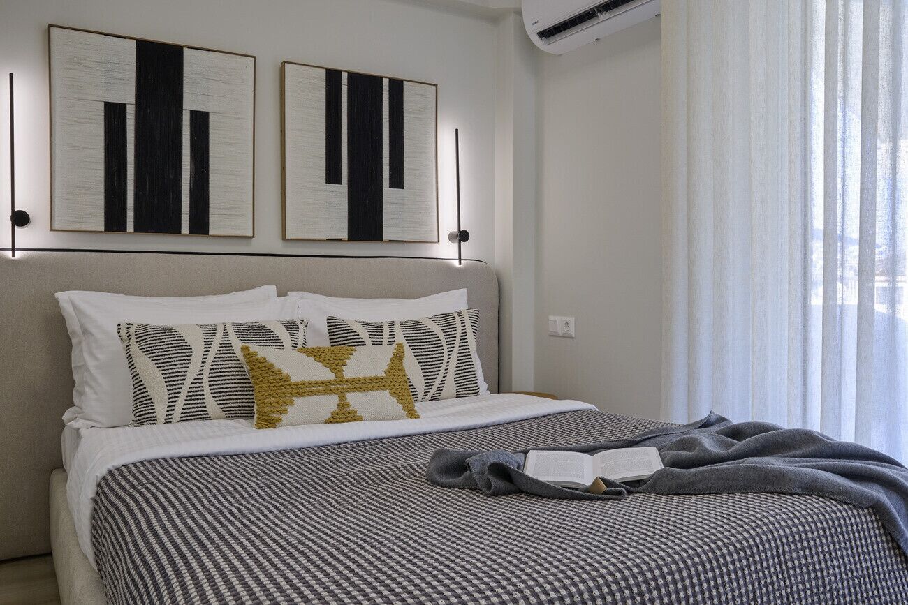 A neatly made bed with a patterned bedspread, two pillows with a geometric design, and a book on the bed.