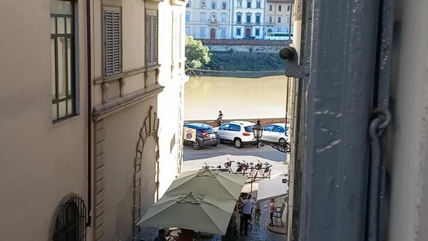 A narrow street with parked cars and a café with outdoor seating. - Le Stanze dei Ghibellini (Florence)