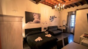 A hotel room with a bed, a sofa, a dining table, and a chandelier. - Le Stanze dei Ghibellini (Florence)