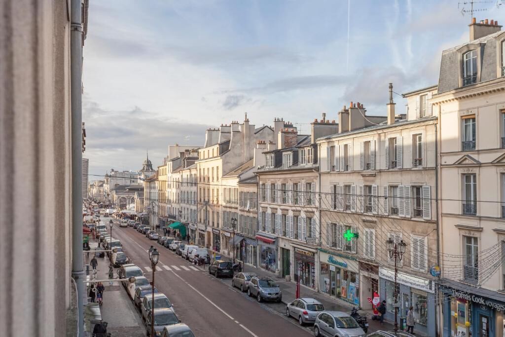 A street view with buildings, parked cars, and a few pedestrians.