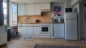 Een moderne keuken met witte kasten, een houten aanrecht, een fornuis, een vaatwasser en een koelkast.