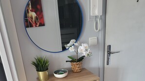 Een houten bureau met een spiegel, een telefoon en een mand met bloemen.