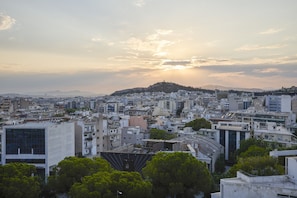 Un paisaje urbano con una colina destacada al fondo, numerosos edificios y un cielo despejado.