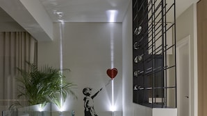 Un interior moderno con barandilla de vidrio, una planta en maceta, un estante en la pared y una escalera.